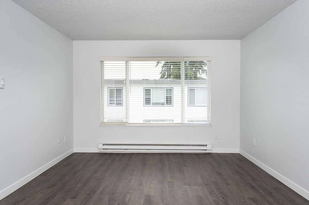 an empty room with wood floors and a window